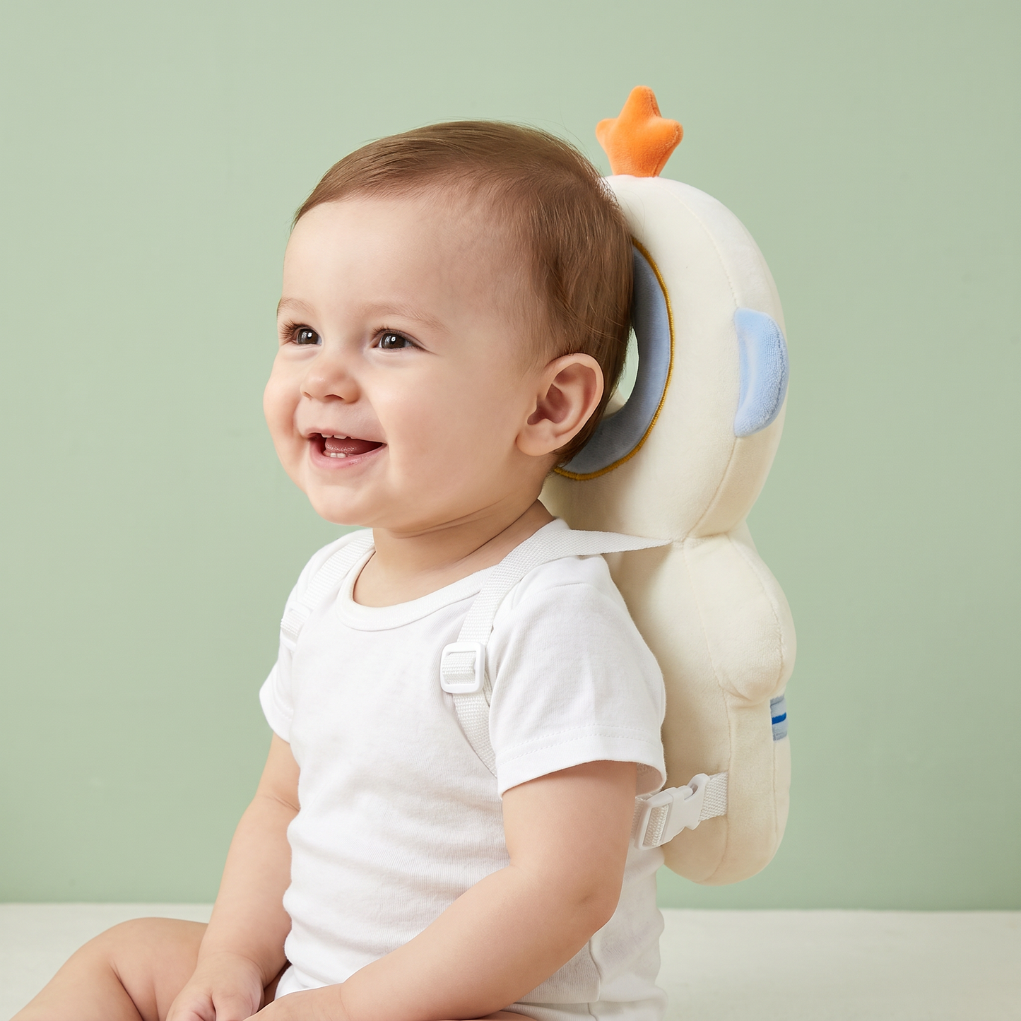 Bébé souriant portant le coussin Coconia Astronaute Étoile - vue de face 3/4, anneau de protection visible derrière la tête