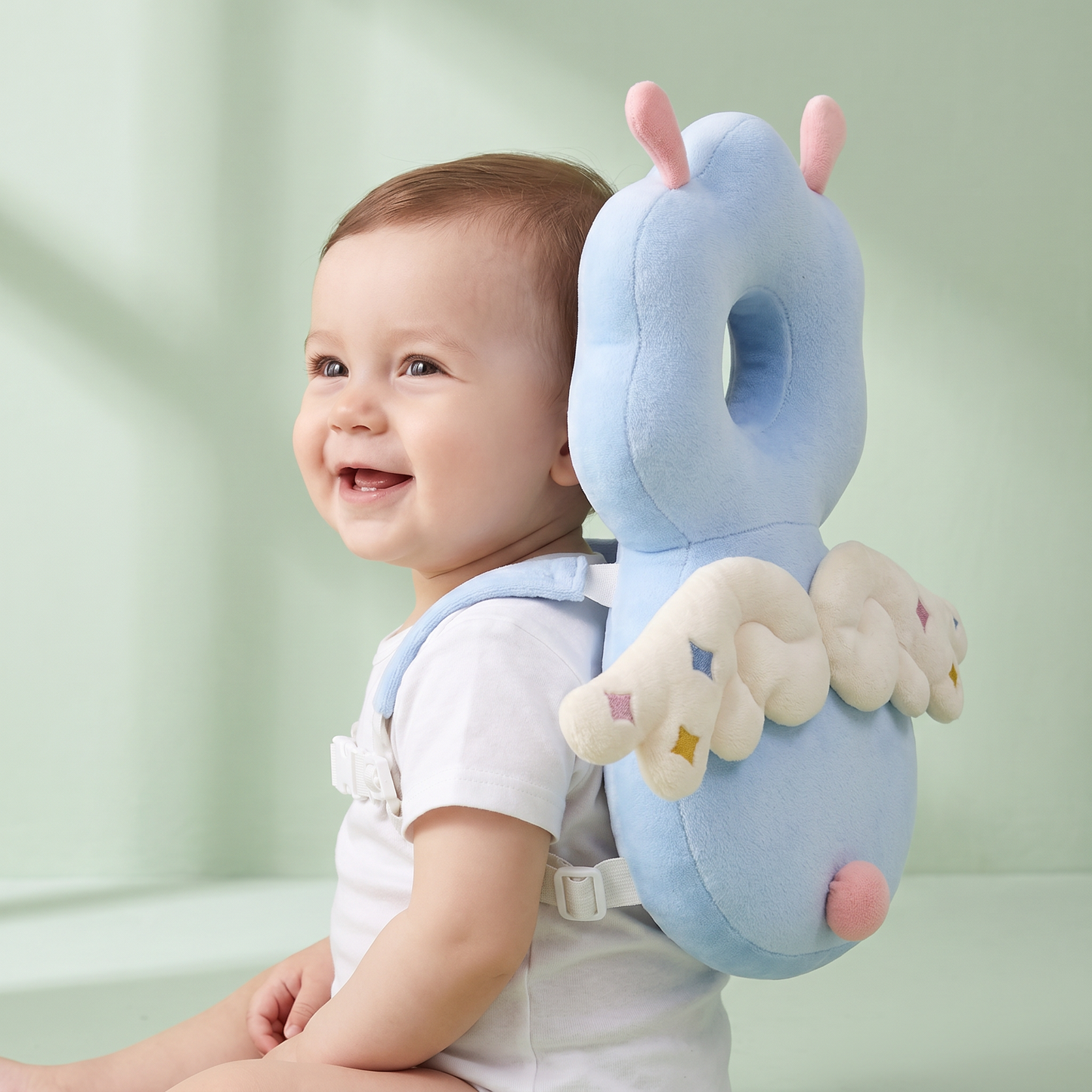 Bébé debout portant le coussin Coconia Ange Nuage - vue de dos, ailes blanches protectrices visibles, tête encadrée par le coussin