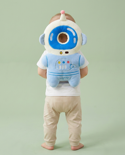 Bébé debout portant le coussin Coconia Astronaute Cosmo - vue de dos, casque blanc encadrant la tête, corps bleu plush
